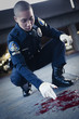 Asian policeman examining blood on ground