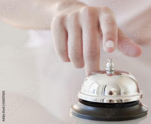 Photo: Woman tapping hotel service bell Woman tapping hotel service bell
