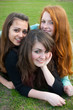Three different girls are laying on the grass and hugging Three different girls are laying on the grass and hugging