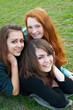 Three different girls are laying on the grass and hugging Three different girls are laying on the grass and hugging