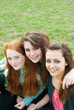 Three different girls are sitting on the grass and hugging Three different girls are sitting on the grass and hugging