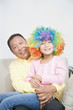 Chinese grandfather holding granddaughter with clown wig