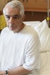 Elderly man sitting on hospital bed