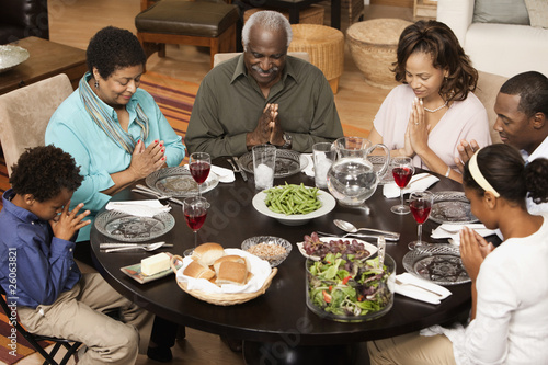 Photo: Multi-generation family saying grace at dinner table Multi-generation family saying grace at dinner table