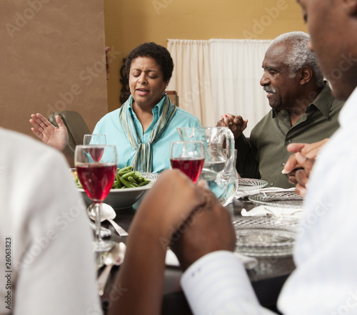 Photo: Family saying grace at dinner table Family saying grace at dinner table