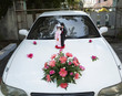 Bride and groom statuettes on hood of car
