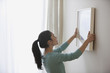 Mixed race woman hanging picture on wall