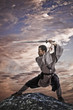 Mixed race martial artist holding sword on rock