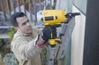 Hispanic man drilling siding on house