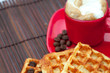 cup of cappuccino wafers and coffee beans on a bamboo mat