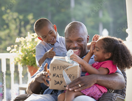 Photo: Boy and girl watching father open Father's Day gift Boy and girl watching father open Father's Day gift