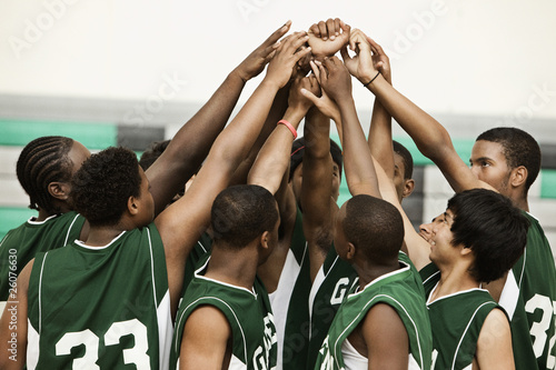 Photo: Basketball team with arms raised in huddle Basketball team with arms raised in huddle