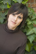 Hispanic woman leaning on ivy-covered wall