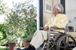 Elderly Hispanic man in wheelchair looking out window