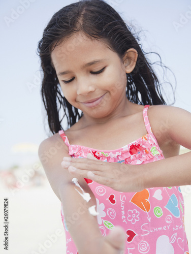 Photo: Hispanic girl applying sunscreen lotion Hispanic girl applying sunscreen lotion
