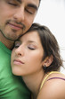 Hispanic couple hugging with eyes closed