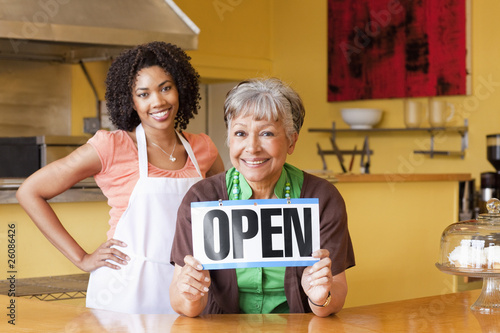Photo: African American business owners in cafe holding open sign African American business owners in cafe holding open sign
