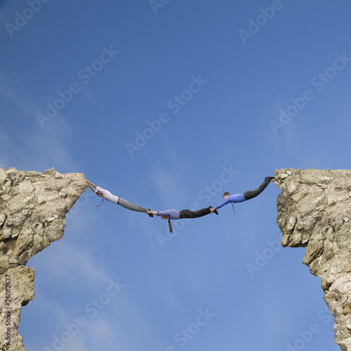 Foto: Businessmen holding hands and feet to bridge cliffs Businessmen holding hands and feet to bridge cliffs