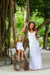 Young beautiful mother and her little daughter in tropical park
