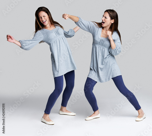 Photo: Psycho young woman hiting herself on grey background Psycho young woman hiting herself on grey background