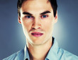 Smart young guy looking serious against grey background