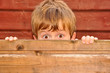 Kind versteckt sich hinter einer Holzwand
