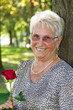 Ältere Frau (Seniorin) mit einer roten Rose