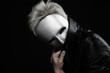 gloomy woman in silver mask posing on a black background