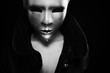 gloomy woman in silver mask posing on a black background