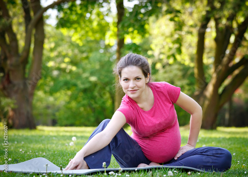Photo: Beautiful pregnant woman exercising in the park Beautiful pregnant woman exercising in the park