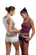 Two women measure waist belly by metre-stick Two women measure waist belly by metre-stick