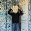 Figure obscured by torn wallpaper in abandoned house.