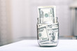 Many 100 US dollars bank notes in a glass jar