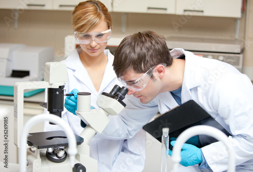 Photo: Two scientists observing something with a microscope Two scientists observing something with a microscope