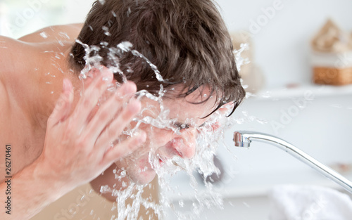 Photo: Bright caucasian man spraying water on his face after shaving in Bright caucasian man spraying water on his face after shaving in