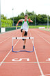 Sporty man jumping above hedge during a race