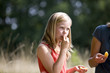 A young girl sitting on the grass, eating an orange