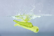 green chilli thrown in water with gray background