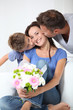 Father and son kissing mother for her birthday