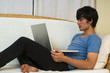 Young Asian man using computeron sofa