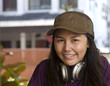 Happy young Asian girl with headphones and a hat