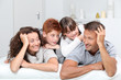 Happy family of 4 people laying on a sofa at home
