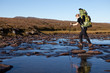 female hiker is crossing the river female hiker is crossing the river
