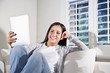 Photo: Hispanic woman reading electronic book on couch Hispanic woman reading electronic book on couch