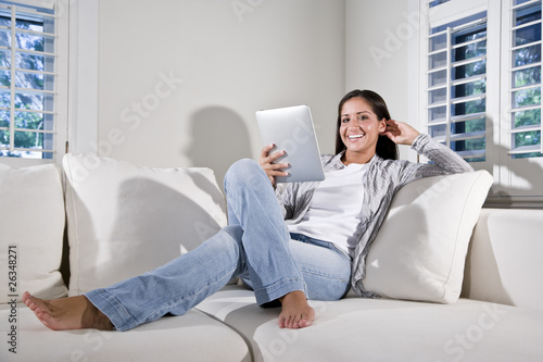 Photo: Hispanic woman reading electronic book on couch Hispanic woman reading electronic book on couch