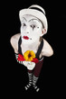 Funny mime in white hat with a bouquet of flowers on a black bac
