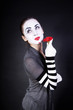 woman mime with theatrical makeup and red flower in hands