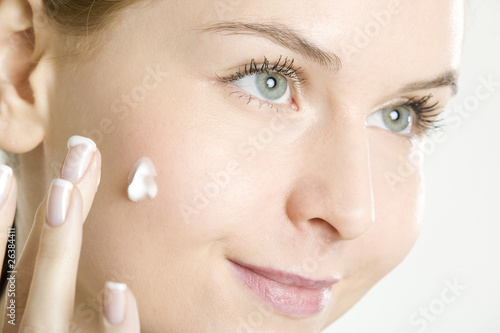 Photo: portrait of woman putting cream on face portrait of woman putting cream on face