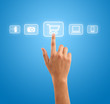 Hand pressing shopping cart symbol from media icons on blue back Hand pressing shopping cart symbol from media icons on blue back
