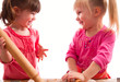 two little girls with rolling pins baking cookies two little girls with rolling pins baking cookies